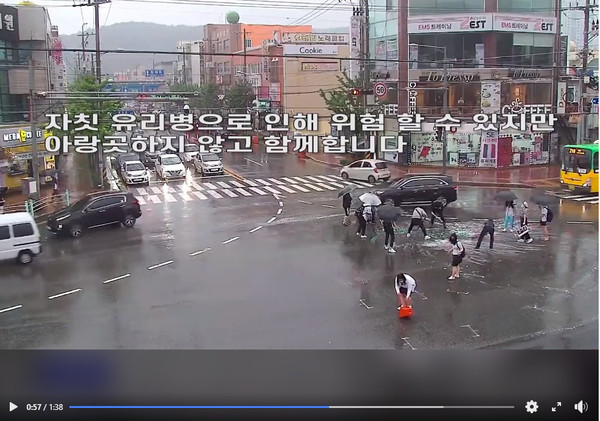 교차로 근처를 지나던 포항 세명고등학교 학생 9명이 비가 오는 궂은 날씨에도 쏟아진 소주 박스와 소줏병 파편들을 치우고 있다.