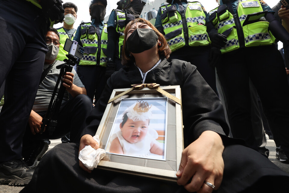 16개월 된 입양아 정인양을 학대해 숨지게 한 혐의를 받는 양부모의 1심 선고 공판이 열린 14일 오전 서울 양천구 서울남부지법 앞에서 한 시민이 정인이 사진을 끌어안은 채 눈물을 흘리고 있다. / 연합뉴스