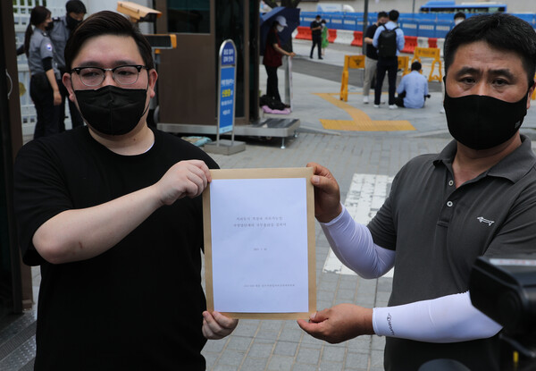 코로나19 대응 전국자영업자비대위 김기홍 대표(왼쪽)가 16일 정부서울청사 앞에서 국무총리실에 전달하는 거리두기 4단계 조치에 대한 질의서를 들고 있다./ 연합뉴스