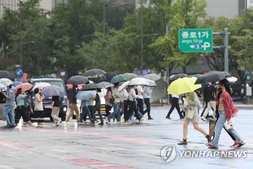 세종대로 사거리에서 우산을 쓴 시민들이 길을 건너고 있다./ 연합뉴스