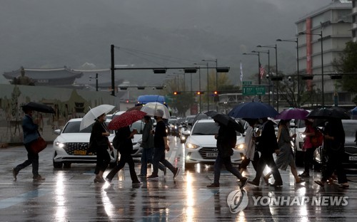 비가 내린 서울 광화문광장에서 시민들이 우산을 쓴 채 걸어가고 있다./ 연합뉴스