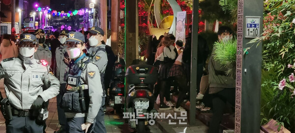 31일 자정이 넘은 시각. 용산구 이태원 길거리에 방역수칙을 어기고 음주를 하고 있는 시민들 속 경찰관./ 김현우 기자