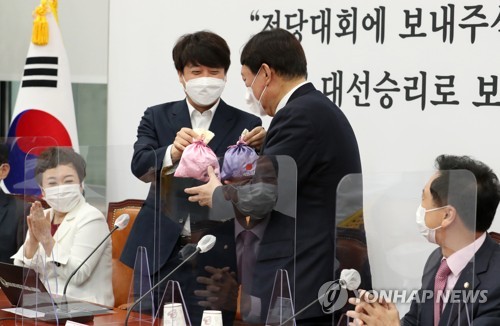 국민의힘 윤석열 대선후보(오른쪽 두번째)가 8일 오전 서울 여의도 국회에서 열린 최고위원회의에서 이준석 대표(왼쪽 두번째)로부터 비단주머니를 받고 있다. /국회사진기자단=연합뉴스