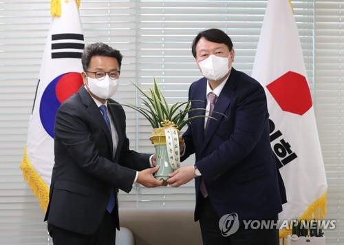 국민의힘 윤석열 대선 후보(오른쪽)가 15일 오후 서울 영등포 국민의힘 당사에서 이철희 청와대 정무수석으로부터 문재인 대통령의 축하 난을 전달받고 있다. /국회사진기자단=연합뉴스