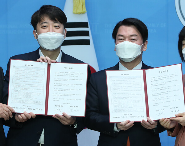 국민의힘 이준석 대표(왼쪽)와 안철수 국민의당 대표가 18일 서울 여의도 국회 소통관에서 기자회견을 열고 합당을 선언한 뒤 합의문을 들어 보이고 있다. /국회사진기자단=연합뉴스