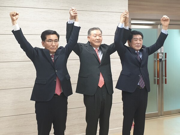 윤건영(왼쪽)·김진균(오른쪽) 후보와 단일화를 중재한 이기용 전 충북교육감이 충북도교육청에서 기자회견을 한 뒤 손을 들고 있다. /연합뉴스