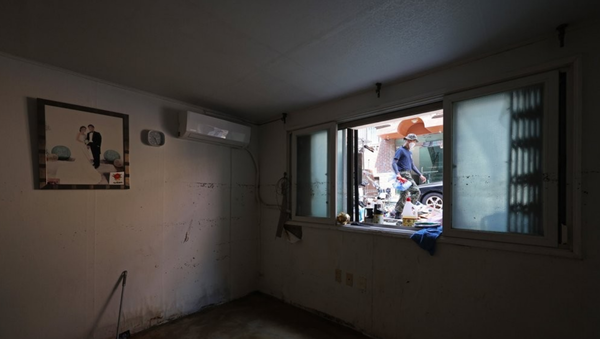 지난 12일 오후 서울 관악구 신림동 일대 반지하에 걸린 부부의 사진 옆 창문틀에 폭우로 침수된 물품들이 널부러져 있다. /연합뉴스