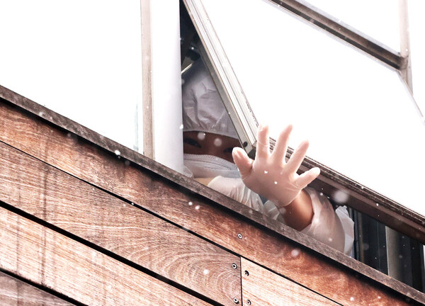 지난해 코호트 격리된 서울 구로구의 한 요양시설에서 함께 격리된 종사자가 외부 취재진을 향해 손을 흔들고 있다. /연합뉴스