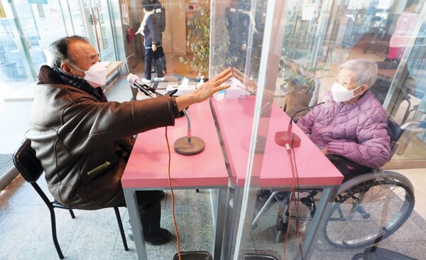 대전시의 한 요양원에서 한 여성 어르신 입소자가 남편과 비대면으로 면회하고 있다. /연합뉴스