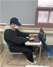 한 대학생이 강의실의 일체형 책상에 앉아 노트북을 사용하고 있다. 팔을 뻗어 키보드를 눌러야 하는 불편함으로 인해 결국 거북등 모양으로 작업을 하게 된다. /사진=이지훈 학생