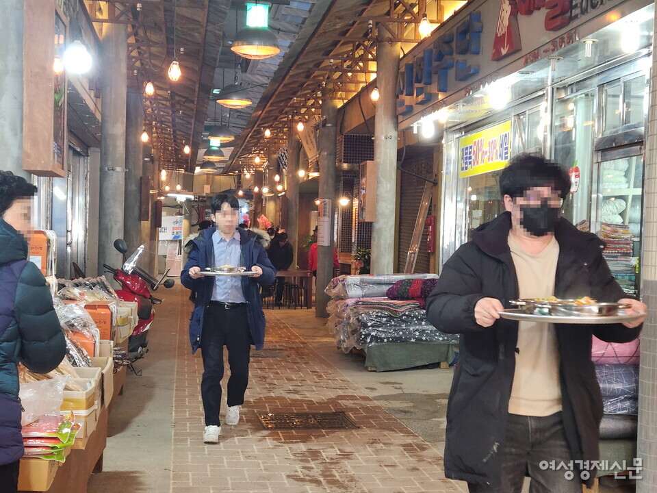 주문한 먹거리를 시장 중앙의 식탁으로 가져가는 시민들의 모습. /김혜선 기자