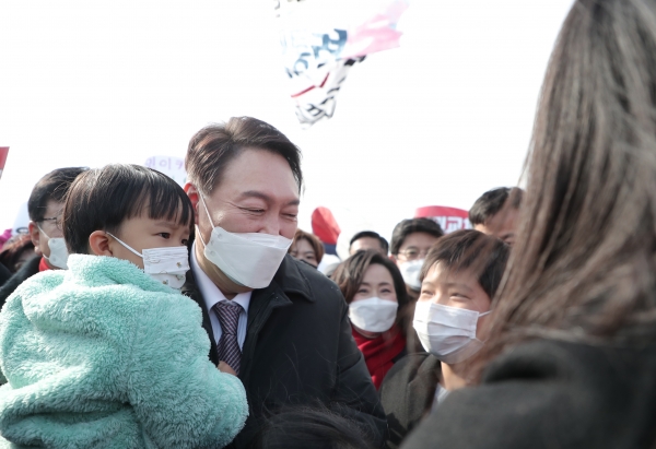 지난해 2월 당시 윤석열 국민의힘 대선 후보가 제주민군복합형 관광미항(제주해군기지)이 있는 서귀포시 강정마을을 방문한 가운데 이곳에 온 어린아이를 안고 있다. /당시 국민의힘 선대위