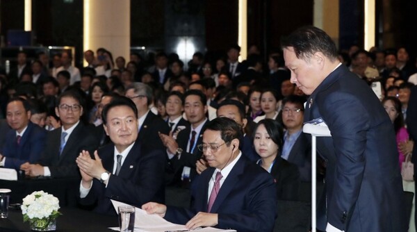 대한상의 회장인 최태원 SK그룹 회장이 지난 6월 23일 하노이 한 호텔에서 열린 한·베트남 비즈니스포럼에서 환영사를 위해 목발을 짚고 나서자 윤석열 대통령이 박수를 보내고 있다. /연합뉴스