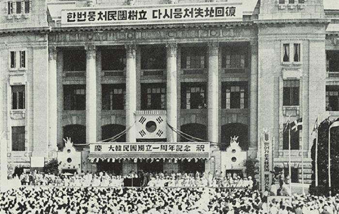 1949년 8월 15일 서울 중앙청 광장에서 열린 ‘대한민국 독립 1주년 기념식’ 모습. 중앙청 건물 윗부분에 내걸린 대형 플래카드에 적힌 문구 ‘한번 뭉처(쳐) 민국 수립, 다시 뭉처 실지 회복’은 독립 1주년을 기념하여 국민에게 공모한 것이었다. /국가기록원