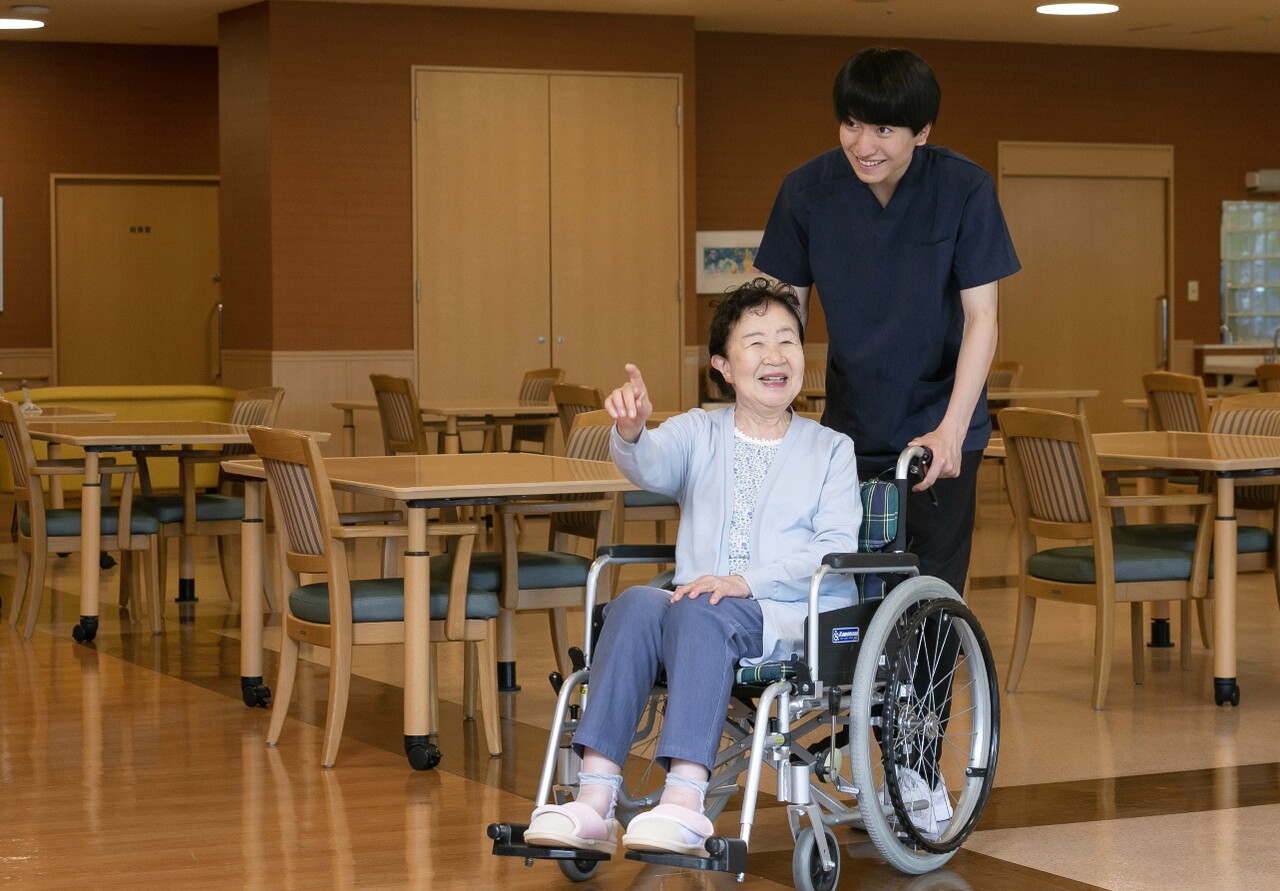 일본은 어르신이 필요한 모든 서비스를 마련하되 개인별 상황에 맞게 선택할 수 있는 시스템을 구축했다. 도움이 필요한 부분에 우선 집중한다는 점도 일본 노인 돌봄의 특징이다. 시설 내 식당에서 휠체어를 타고 이동하는 입주민과 도우미 남성 요양보호사 /솜포케어