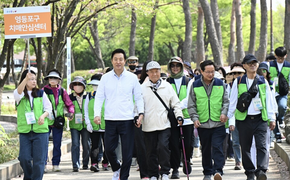 12일 오전 서울 영등포구 여의도공원에서 열린 '제10회 서울시 한마음 치매극복 걷기행사'에서 오세훈 서울시장이 걷기대회에 참여한 어르신과 손을 잡고 걷고 있다. /연합뉴스