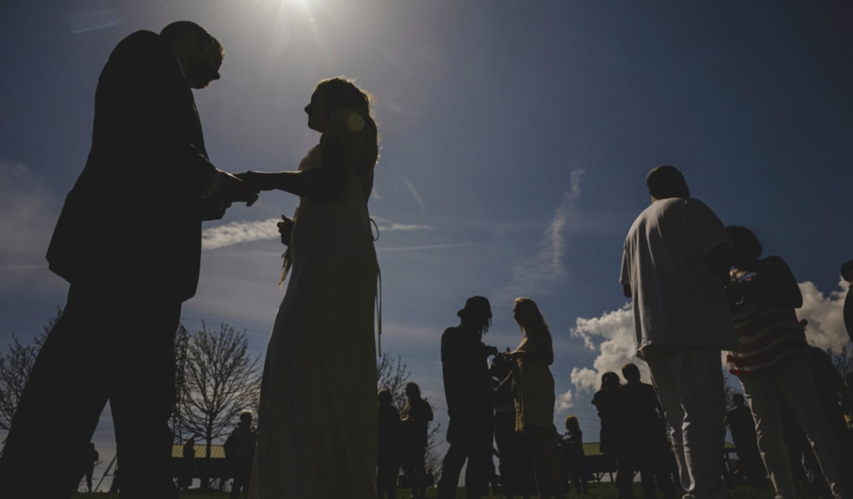 지난 8일(현지시간) 미국 오하이오주 트랜턴 커뮤니티 파크에서 열린 합동결혼식에 참석한 커플들이 개기일식이 진행되는 도중 결혼반지를 교환하고 있다. 이날 미국에서는 북미 대륙에서 7년 만에 관측된 희귀한 우주쇼를 관측하기 위해 많은 사람이 하던 일을 멈추고 하늘을 올려다봤다. /AP=연합뉴스