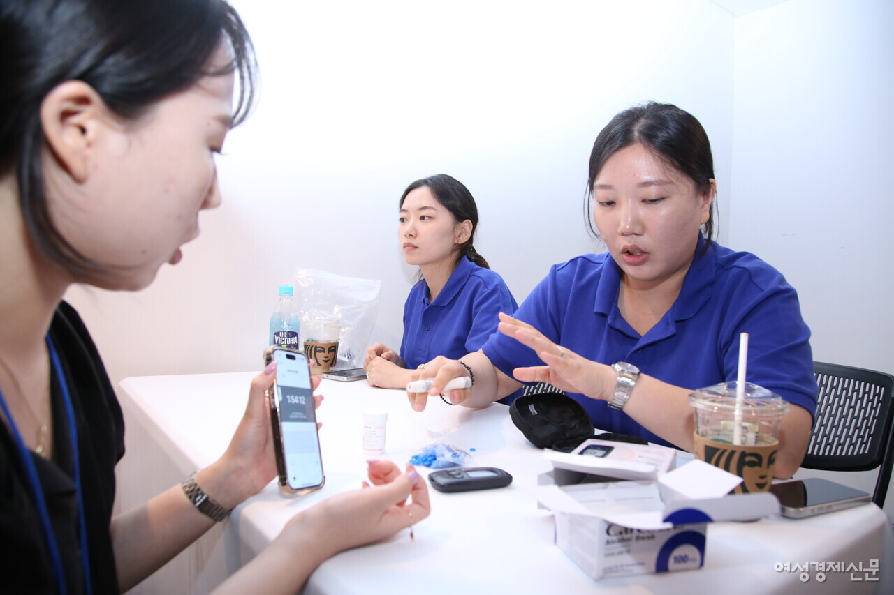 참석자가 아이센스 부스 내 혈당 측정 체험을 진행하고 있다. /류빈 기자