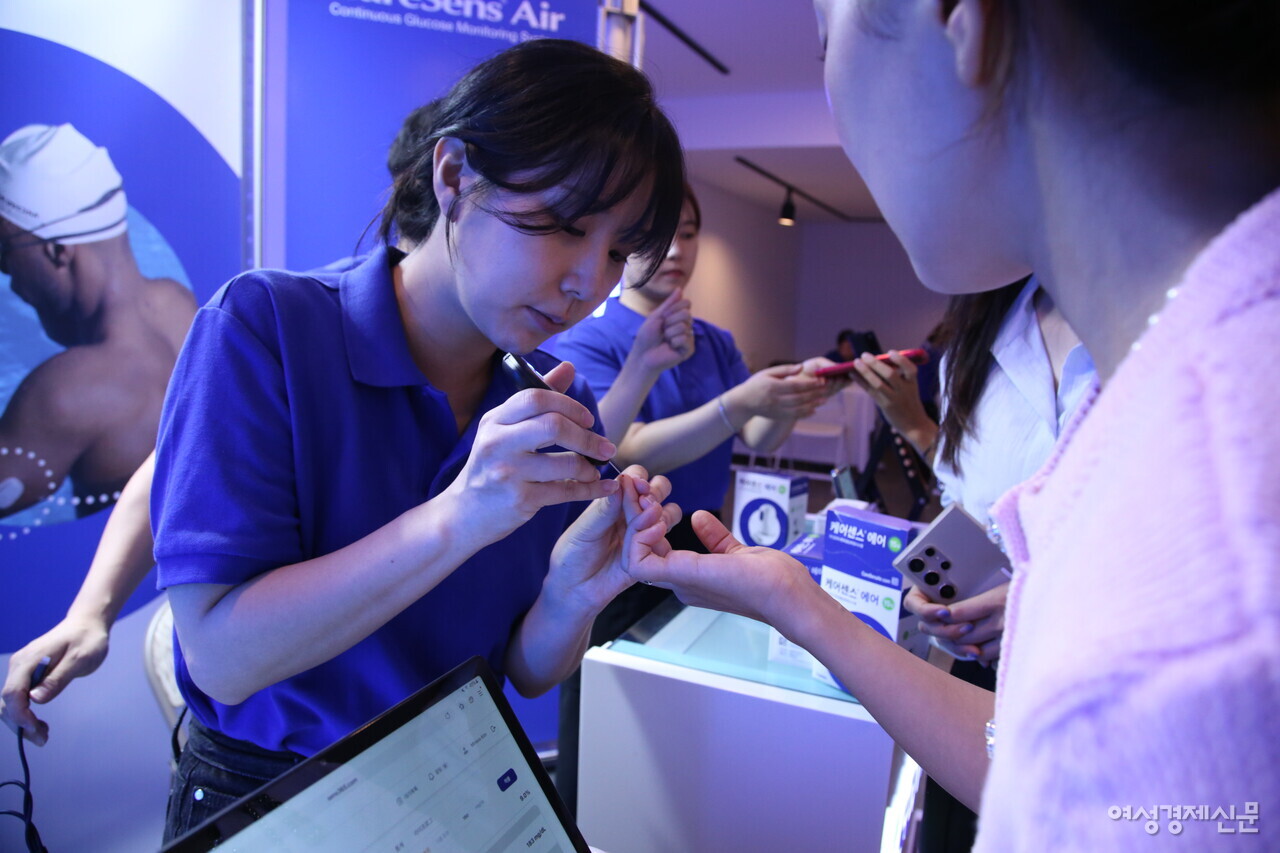 참석자가 아이센스 부스 내 혈당 측정 체험을 진행하고 있다. /류빈 기자