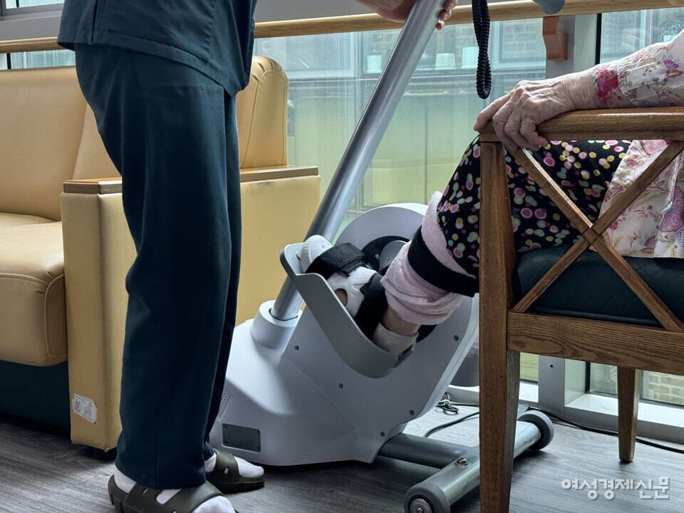 침상생활을 많이 하는 입소어르신이 하지근력운동을 할 수 있도록 요양보호사가 매일 생활실에 마련된 운동기계로 입소어르신을 안내한다. /김현우 기자