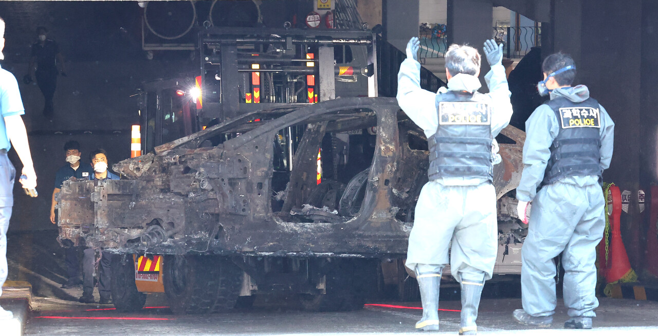 5일 오후 인천 서구 청라동 아파트 지하 주차장 화재 현장에서 합동 감식을 마친 경찰이 화재가 발생한 전기차를 옮기고 있다. 지난 1일 오전 6시 15분께 발생한 전기차 화재로 주민 22명과 소방관 1명 등 모두 23명이 병원으로 옮겨졌으며 차량 40여대가 불에 타고 100여대는 열손과 그을림 피해를 입었다. /연합뉴스