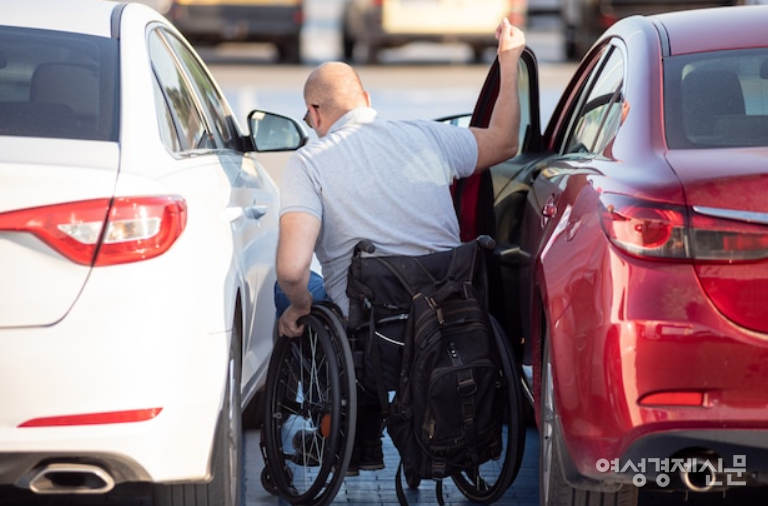 한 장애인 운전자가 운전석에 탑승하고 있다. 하반신 장애인 운전자는 휠체어에서 내려 운전석에 탑승한 후 다시 휠체어를 접어 차에 보관해야 하므로 운전석 공간 확보가 필요하다. /여성경제신문