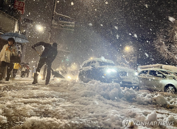 27일 오전, 중부 지역에 많은 눈이 내린 가운데 한 시민이 서울 경복궁역 인근에서 눈을 치우고 있다. /연합뉴스
