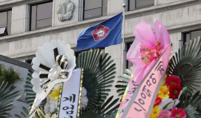 지난 17일 오전 서울 종로구 헌법재판소 앞에 놓인 윤석열 대통령 지지 화환과 반대 화환(왼쪽)사이에 헌재 깃발이 바람에 휘날리고 있다. /연합뉴스