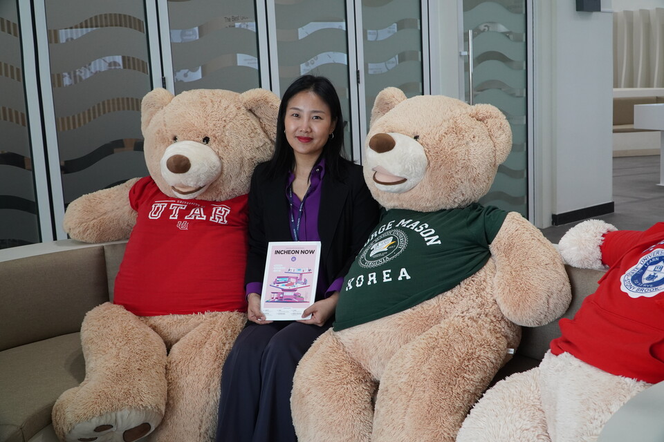 이혜정 주무관이 대학교 티셔츠를 입은 곰돌이 인형 옆에서 시정 소식지 인천나우를 들고 있다. /인천시