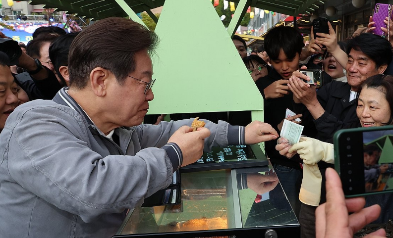 이 후보가 '골목골목 경청투어' 사흘째인 지난 3일 강원도 태백시 장성동 산나물 축제장에서 붕어빵을 사먹으며 지역화폐를 사용하고 있다. /연합뉴스
