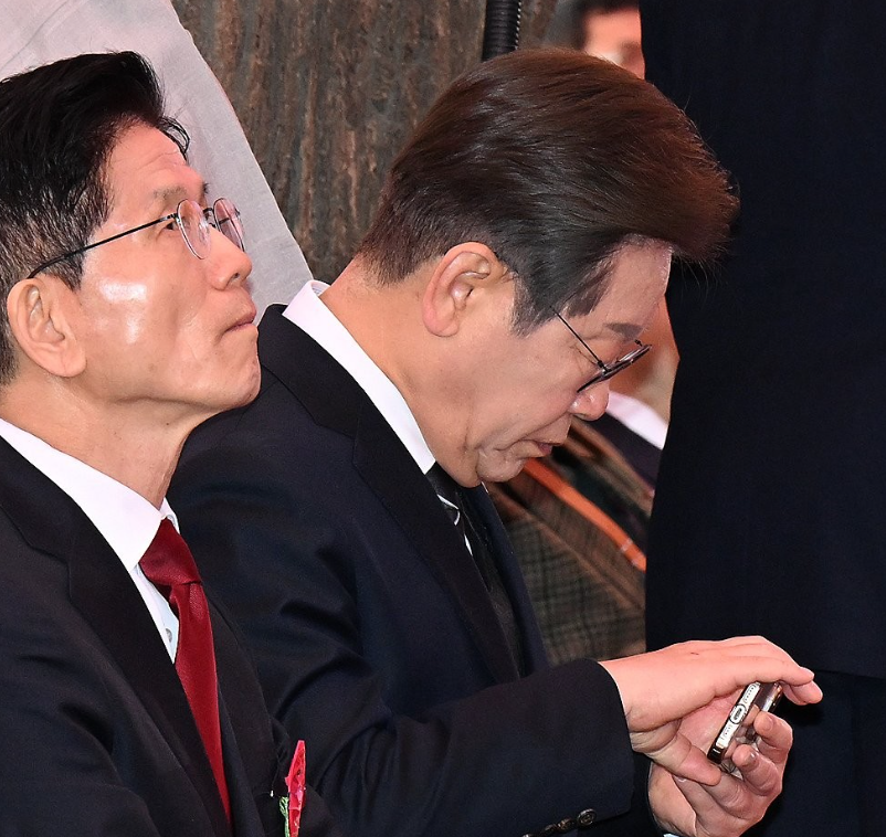 더불어민주당 이재명 대선 후보(오른쪽)가 지난 5일 서울 종로구 조계사에서 열린 불기 2569년 부처님오신날 봉축법요식에서 휴대전화를 확인하고 있다. 이 후보 왼쪽은 국민의힘 김문수 대선 후보. /연합뉴스