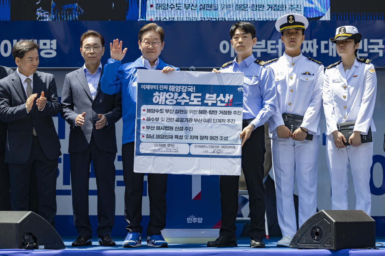 이재명 대통령이 당선 전인 5월 14일 부산 부산진구 서면 젊음의 거리에서 열린 유세에서 권기흥 에이치라인해운해상직원노조 위원장과 해양수도 부산 협약서에 서명한 뒤 기념촬영을 하고 있다. /연합뉴스