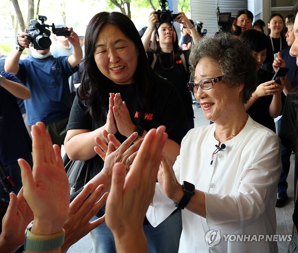 최말자(78)씨가 23일 부산지법에서 열린 재심 첫 공판을 마치고 법정을 나서며 변호인과 여성단체의 박수를 받고 있다. /연합뉴스