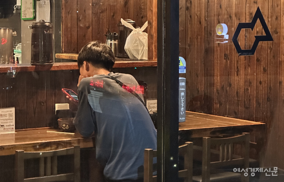 일본 대학들 사이에서 입학 후 1년간 다양한 분야를 경험한 뒤 전공을 결정하는 ‘레이트 스페셜라이제이션’ 제도가 확산 중이다. 학생들은 전담 교수와 선배 멘토의 지원을 받아 진로를 고민하며, 성적에 따라 전공 선택이 결정되기도 한다. 한 청년이 일본 오사카에 위치한 식당에 홀로 앉아 핸드폰을 보며 고민에 잠겨있다. /여성경제신문