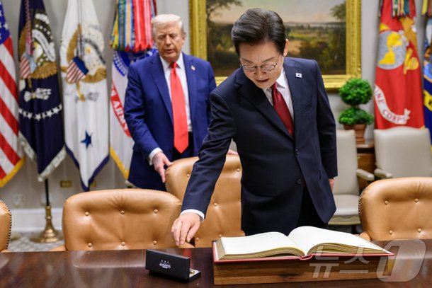 지난 8월 25일(현지시간) 이재명 대통령이 한미정상회담에 앞서 미 백악관 루즈벨트룸에서 방명록에 서명하려고 펜을 잡으려는 순간 도널드 트럼프 미국 대통령이 뒤에서 의자를 당겨 주고 있다. /백악관