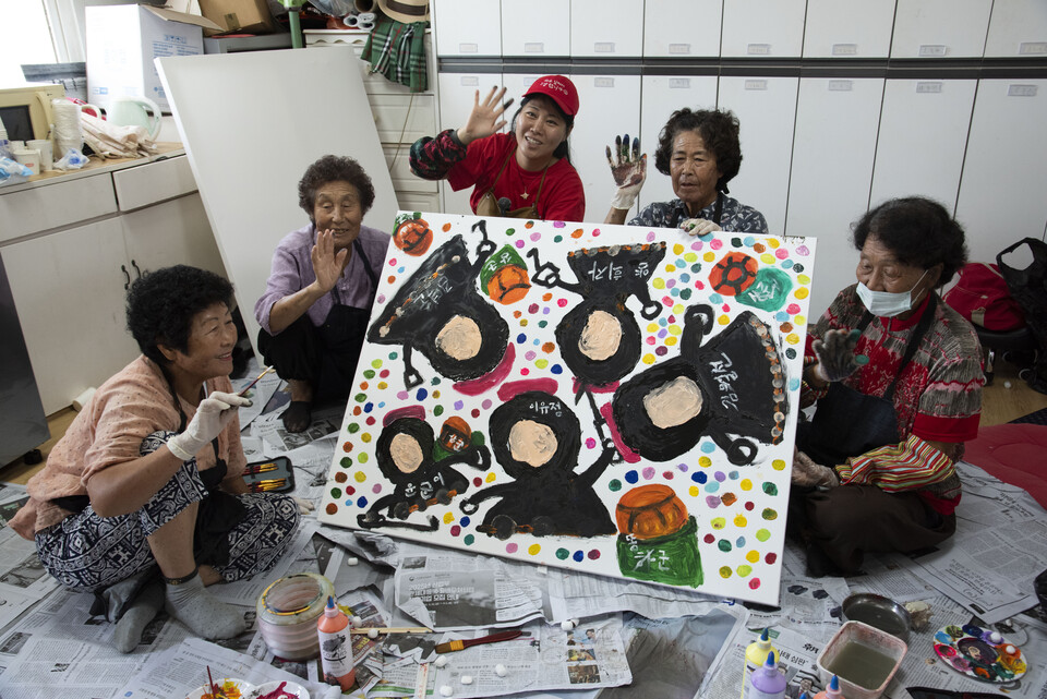 제주 해녀박물관 특별전 「이호해녀의 여름방학」이 12월 14일까지 열린다. 해녀들이 직접 물질 속 빛·파도·성게 등을 회화로 표현하며 ‘노동의 바다’를 ‘쉼과 돌봄’의 공간으로 재해석했다. 사진은 8월 마지막주 이호 해녀탈의실에서 해녀 이유정 씨(가운데)와 해녀 6명이 작품 활동을 하고 있는 모습. /해녀 이유정